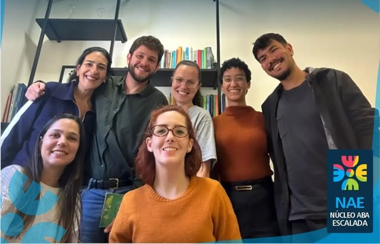 Equipe de psicólogos da Clínica Escalada reunida na sala de supervisão técnica, em frente à estante de livros da clínica